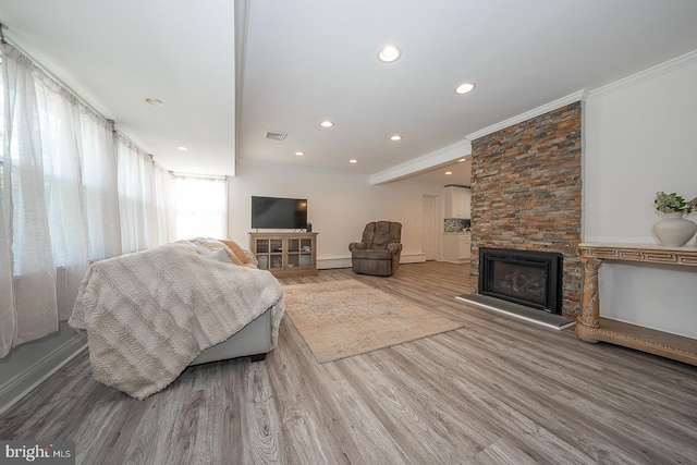 living room featuring a fireplace, ornamental molding, hardwood / wood-style flooring, and a baseboard radiator