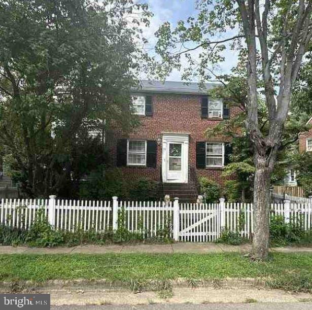 view of front of home featuring brick siding and a fenced front yard