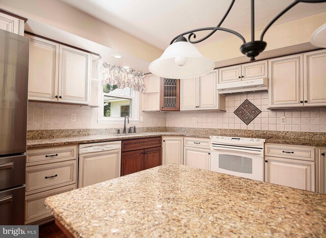 kitchen with white appliances, backsplash, and light stone countertops