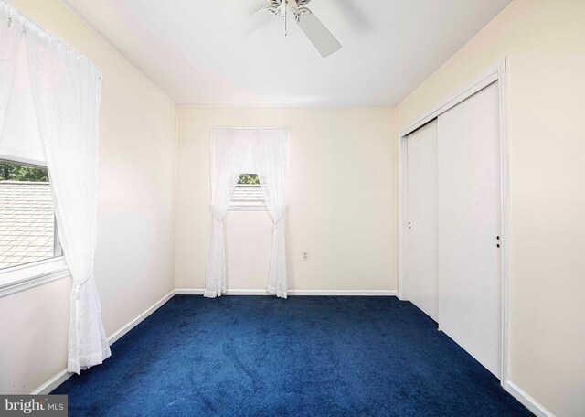 unfurnished bedroom with dark carpet, a closet, and ceiling fan