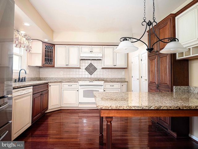 kitchen with white appliances, light stone countertops, sink, dark wood-type flooring, and a kitchen breakfast bar