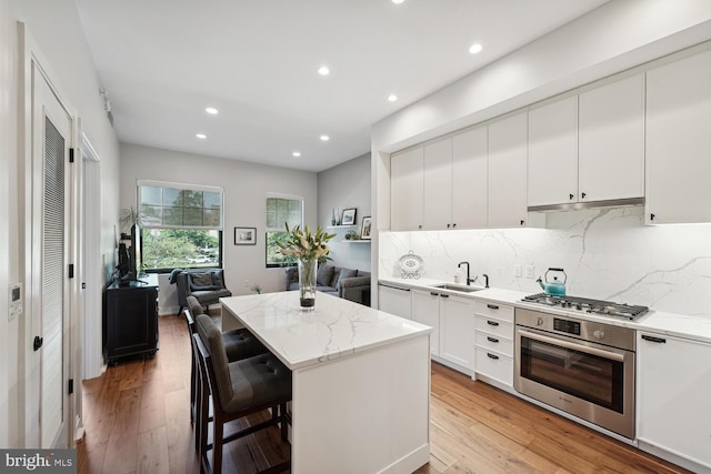 kitchen featuring appliances with stainless steel finishes, light stone counters, and light hardwood / wood-style flooring