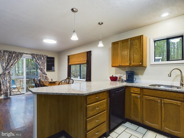 kitchen featuring a textured ceiling, pendant lighting, sink, dishwasher, and light hardwood / wood-style flooring