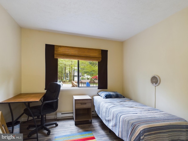 bedroom featuring baseboard heating, dark wood-type flooring, and a textured ceiling