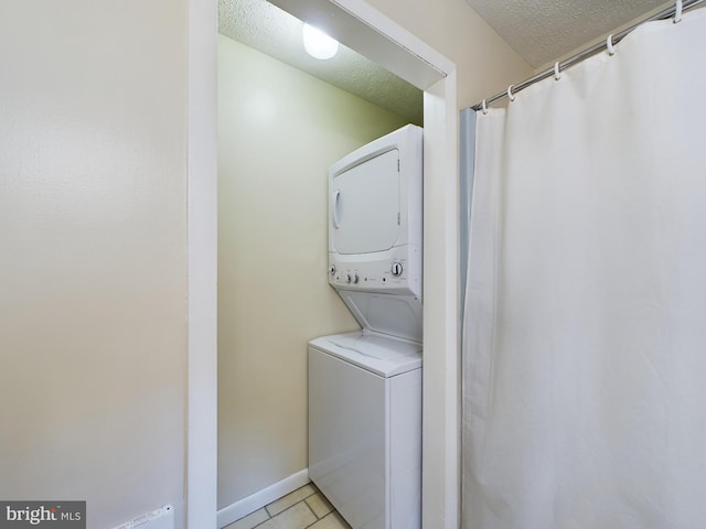 laundry room featuring stacked washing maching and dryer, a textured ceiling, and light tile patterned floors