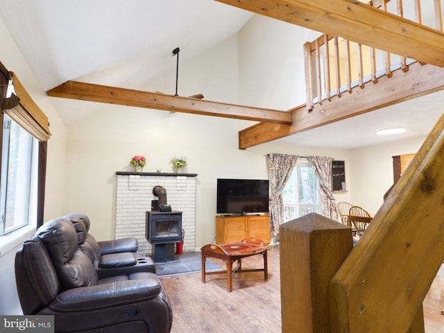 living room featuring wood-type flooring, a wood stove, and high vaulted ceiling