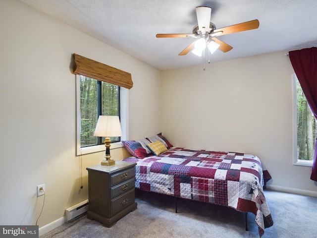 carpeted bedroom with multiple windows, a textured ceiling, ceiling fan, and a baseboard radiator