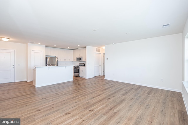 unfurnished living room featuring light wood-type flooring, baseboards, and visible vents