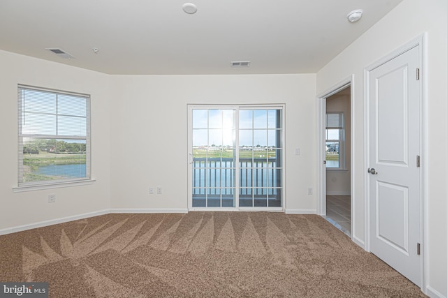 unfurnished room featuring carpet floors, visible vents, and baseboards