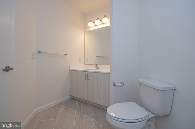 half bath with vanity, toilet, and baseboards