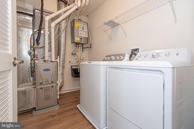 washroom with laundry area, tankless water heater, wood finished floors, and washing machine and clothes dryer