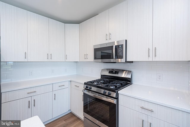 kitchen with appliances with stainless steel finishes, light wood-type flooring, and tasteful backsplash