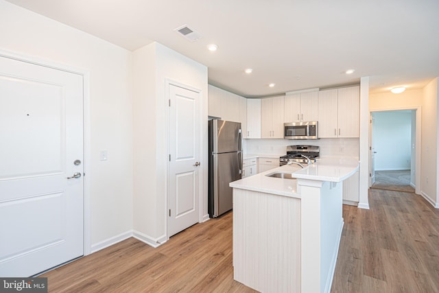 kitchen featuring tasteful backsplash, light countertops, visible vents, appliances with stainless steel finishes, and a sink