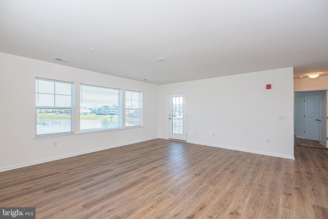 unfurnished living room with light wood-type flooring, visible vents, and baseboards