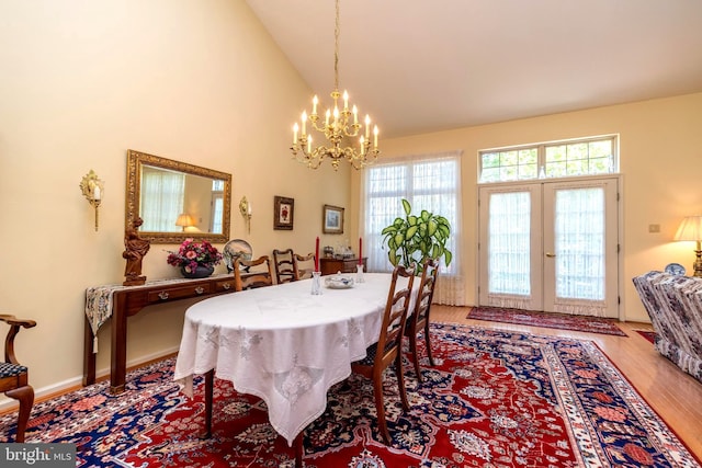 dining area with french doors, an inviting chandelier, hardwood / wood-style floors, and high vaulted ceiling