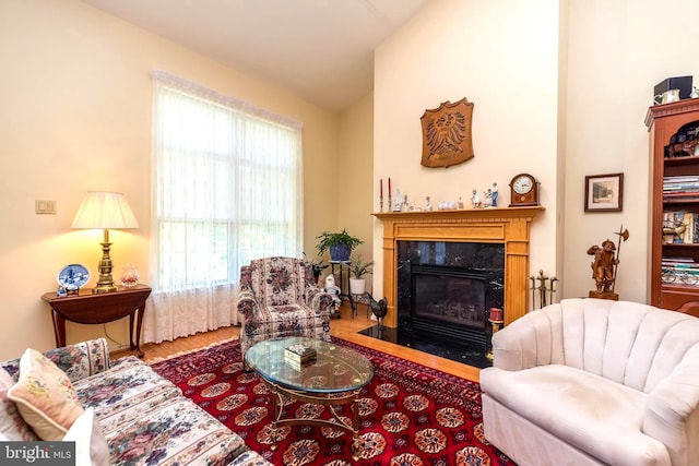 living room with lofted ceiling, hardwood / wood-style floors, a high end fireplace, and plenty of natural light