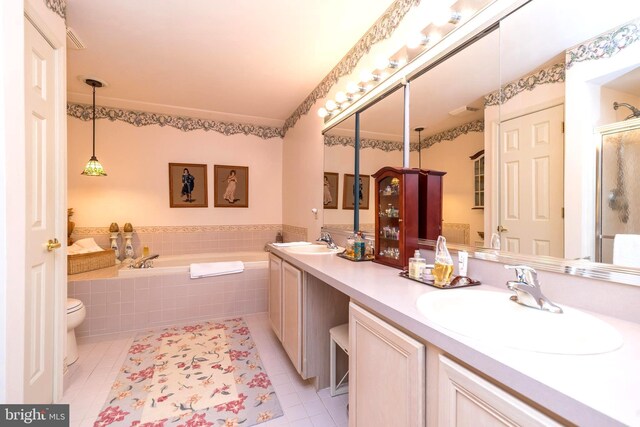 bathroom with tiled tub, vanity, toilet, and tile patterned flooring