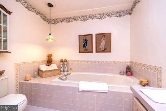 bathroom with vanity, a relaxing tiled tub, and toilet