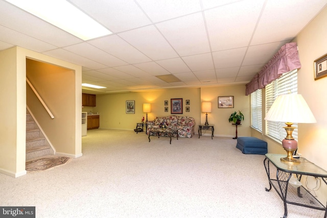 living area featuring a drop ceiling and carpet flooring