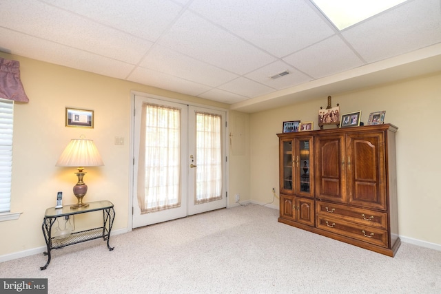 sitting room featuring light carpet, a drop ceiling, and french doors