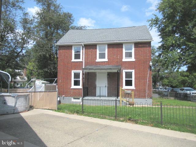 townhome / multi-family property with brick siding, a fenced front yard, a front lawn, and a fenced in pool