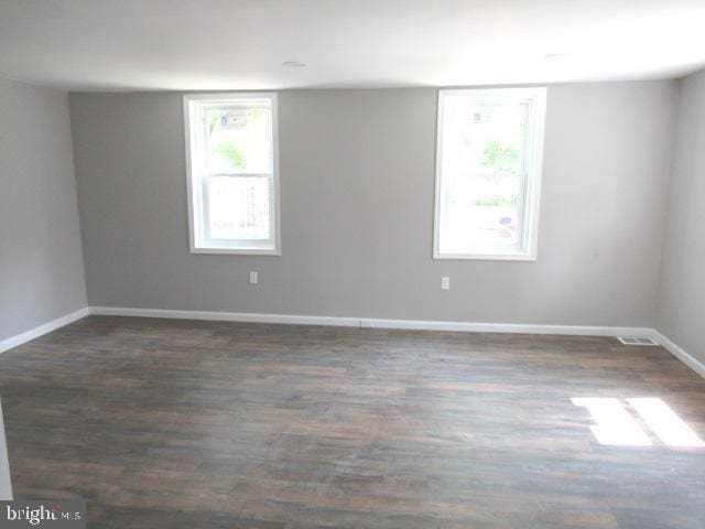 spare room with a wealth of natural light and dark hardwood / wood-style floors