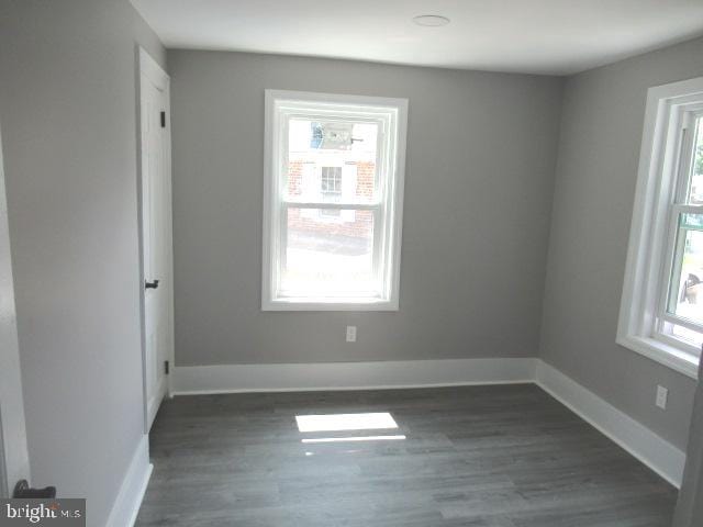 spare room featuring dark hardwood / wood-style flooring and a wealth of natural light