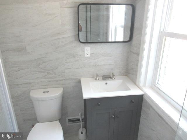 bathroom featuring vanity, tile walls, toilet, and plenty of natural light