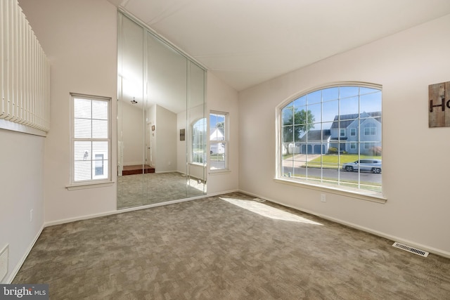 carpeted empty room featuring vaulted ceiling and a wealth of natural light