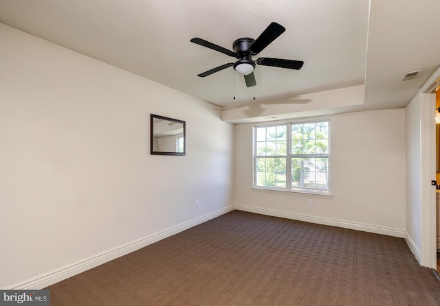 empty room with ceiling fan and dark colored carpet