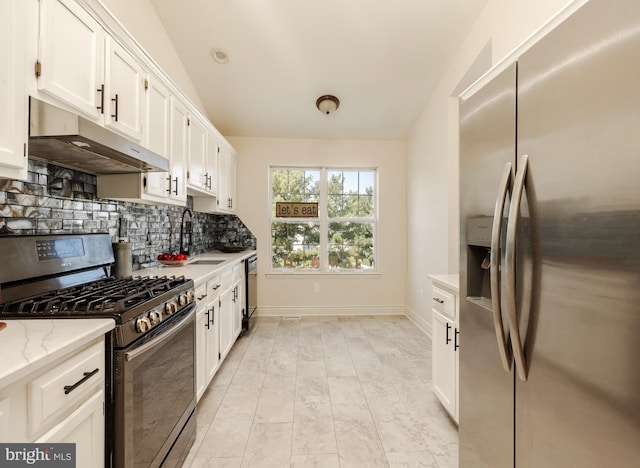 kitchen featuring lofted ceiling, backsplash, appliances with stainless steel finishes, light stone counters, and white cabinetry