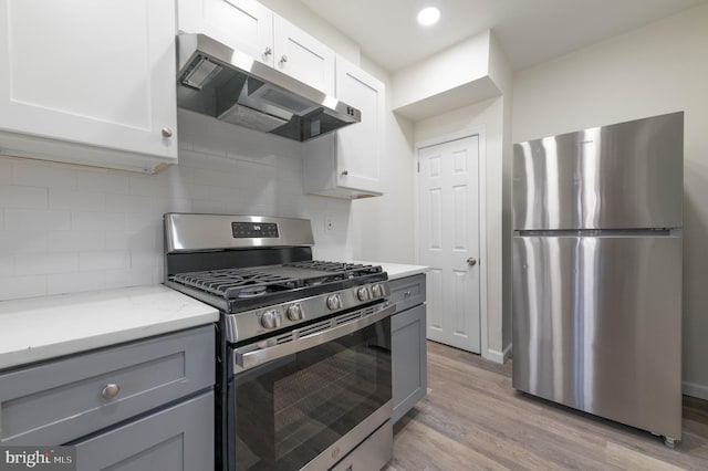 kitchen with white cabinets, gray cabinetry, appliances with stainless steel finishes, light hardwood / wood-style floors, and tasteful backsplash