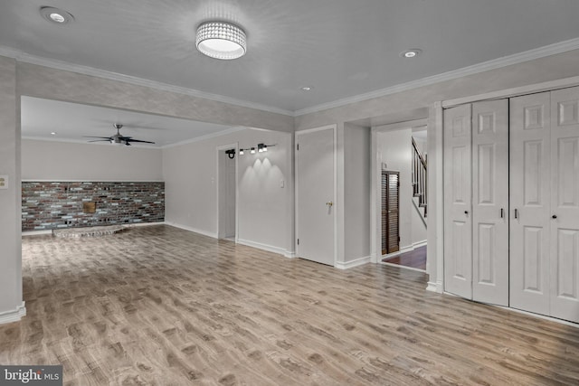 unfurnished living room featuring ceiling fan, light hardwood / wood-style flooring, crown molding, and brick wall