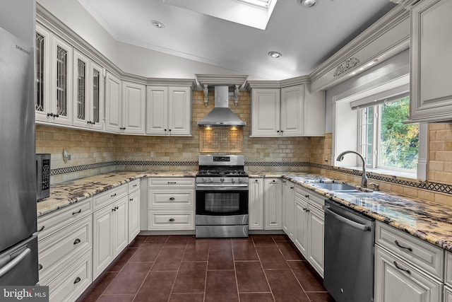 kitchen with sink, white cabinetry, wall chimney range hood, backsplash, and appliances with stainless steel finishes