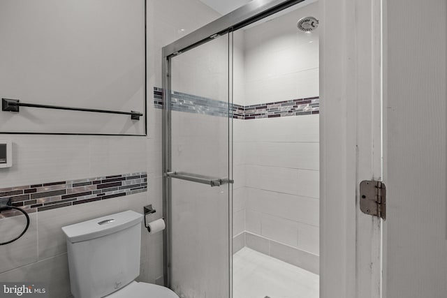 bathroom with tile walls, an enclosed shower, and toilet