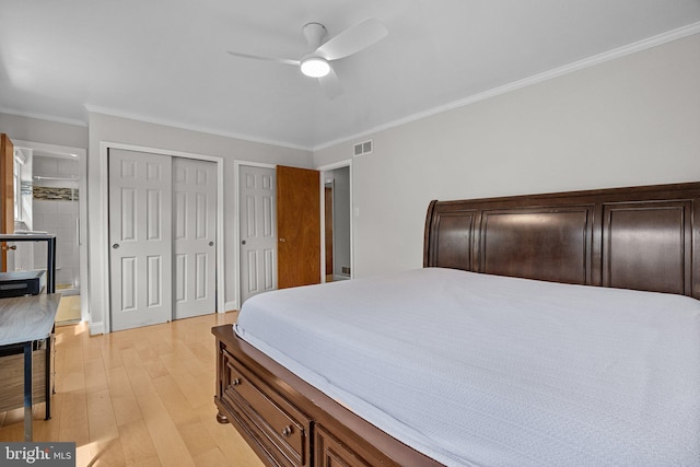 bedroom with ceiling fan, light hardwood / wood-style flooring, crown molding, and two closets