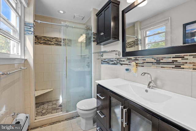 bathroom featuring a healthy amount of sunlight, a shower with door, vanity, and toilet