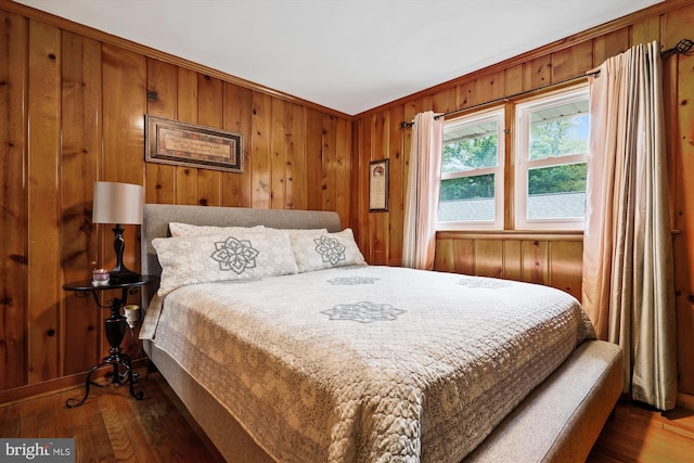 bedroom featuring ornamental molding, wooden walls, and dark hardwood / wood-style floors