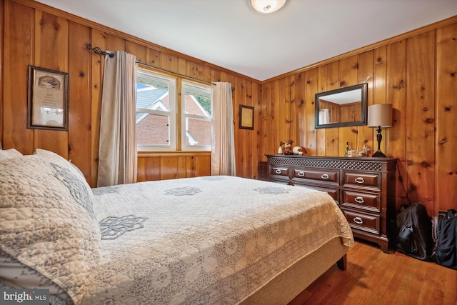 bedroom featuring wood walls, hardwood / wood-style floors, and crown molding