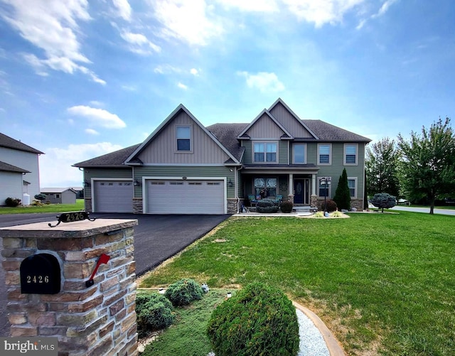 craftsman house featuring aphalt driveway, an attached garage, stone siding, board and batten siding, and a front yard