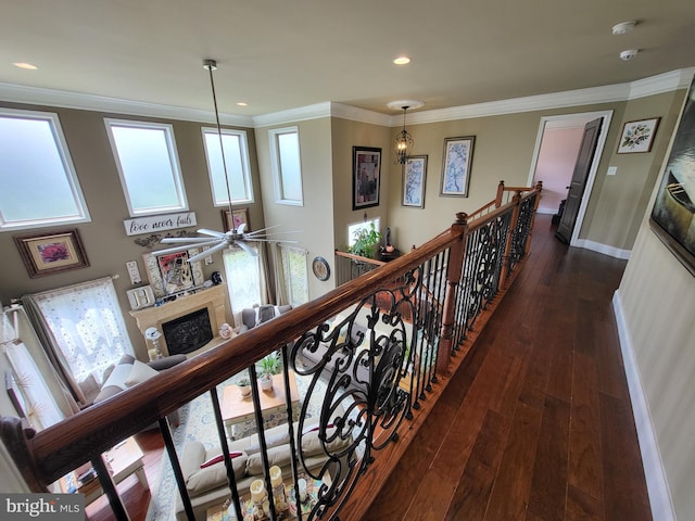 hall featuring crown molding, baseboards, dark wood-type flooring, and an upstairs landing