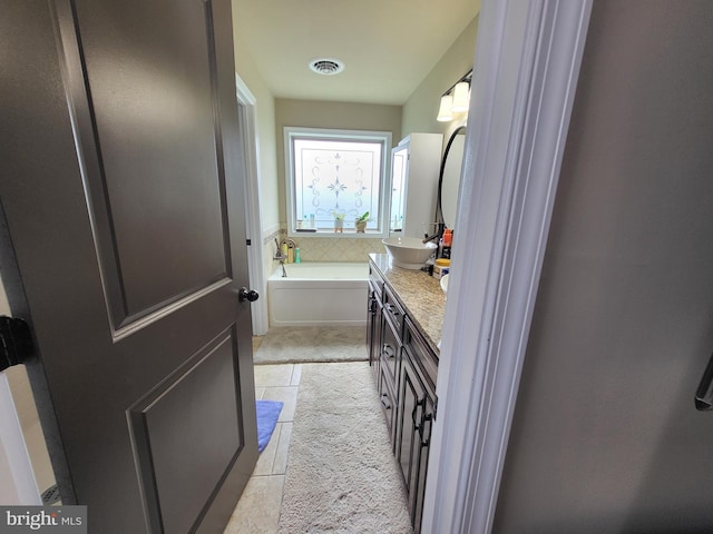 bathroom featuring a garden tub, tile patterned floors, visible vents, and vanity