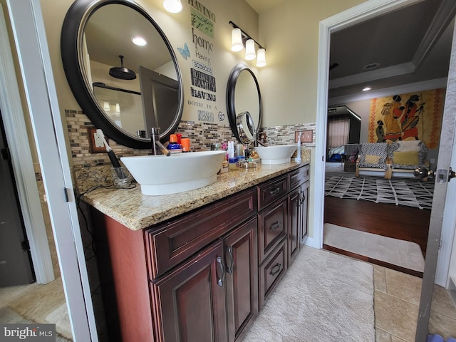 full bath with double vanity, crown molding, decorative backsplash, and a sink