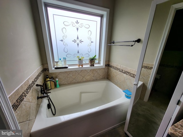 full bath with a garden tub, tile walls, and wainscoting