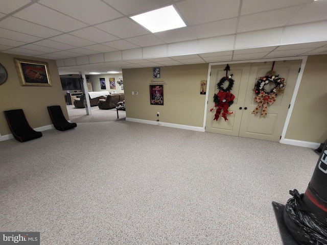 finished basement with carpet floors, a drop ceiling, and baseboards