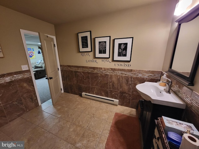 bathroom with a baseboard radiator, a wainscoted wall, and tile walls