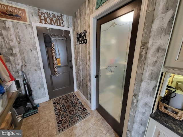 doorway to outside with light tile patterned floors, baseboards, and wallpapered walls