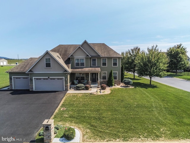 craftsman inspired home featuring stone siding, a front lawn, a shingled roof, and aphalt driveway