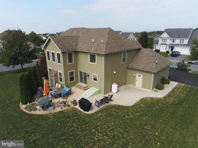 back of house featuring entry steps, a yard, roof with shingles, and a patio