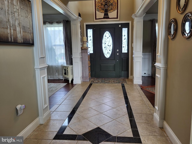 foyer entrance with decorative columns and baseboards